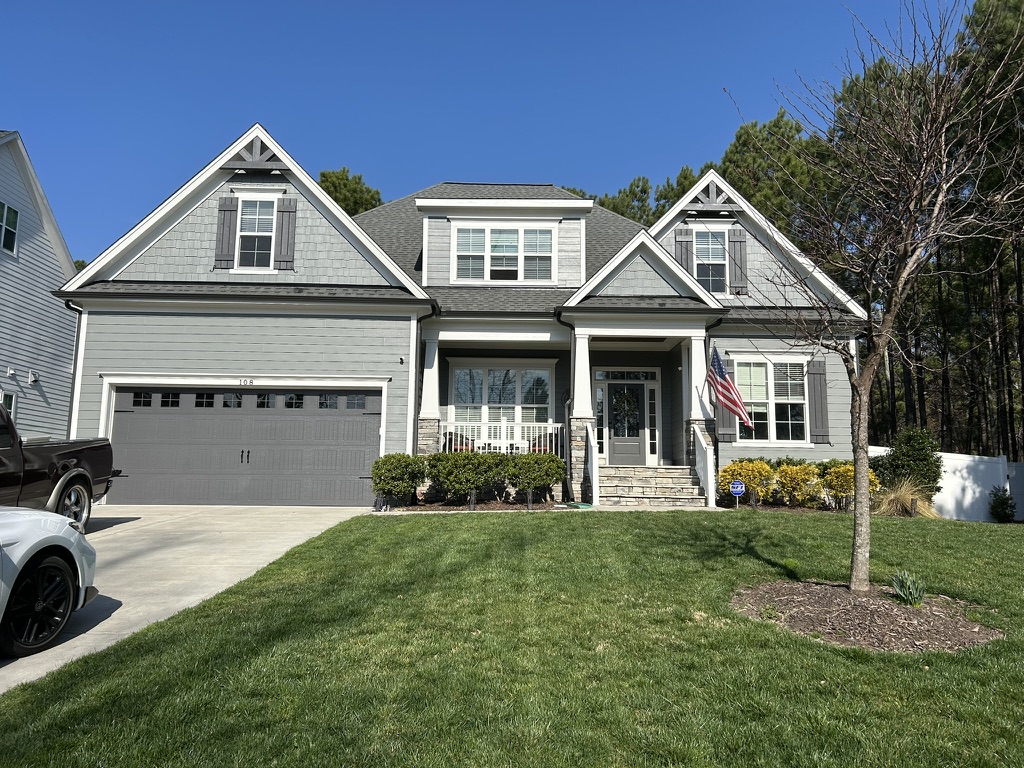 Gray home exterior with white trim, dark shutters, and a front porch